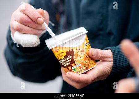 Brême, Allemagne.24th décembre 2021.Un homme sans abri tient un repas chaud qu'il a reçu du bus froid Johannître sur la piste à la gare principale la veille de Noël.À plusieurs endroits à Brême, des repas chauds ou des sacs avec de la nourriture et des cadeaux sont distribués aux sans-abri et aux personnes dans le besoin à la veille de Noël.Credit: Hauke-Christian Dittrich/dpa/Alay Live News Banque D'Images