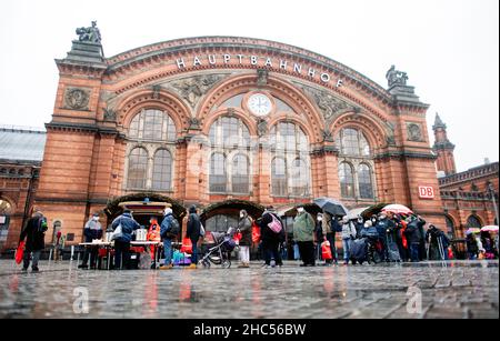 Brême, Allemagne.24th décembre 2021.De nombreuses personnes dans le besoin font la queue devant le bus Johannitre pour temps froid sur la piste de la gare principale la veille de Noël.À plusieurs endroits de Brême, des repas chauds ou des sacs avec de la nourriture et des cadeaux sont distribués aux sans-abri et aux personnes dans le besoin à la veille de Noël.Credit: Hauke-Christian Dittrich/dpa/Alay Live News Banque D'Images