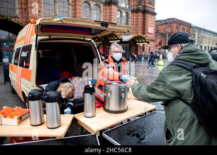 Brême, Allemagne.24th décembre 2021.Karin Stelljes, chef d'équipe au bus froid Johanniter, remet un repas chaud à une personne dans le besoin la veille de Noël sur la piste de la gare principale.À plusieurs endroits à Brême, des repas chauds ou des sacs avec de la nourriture et des cadeaux sont distribués aux sans-abri et aux personnes dans le besoin à la veille de Noël.Credit: Hauke-Christian Dittrich/dpa/Alay Live News Banque D'Images