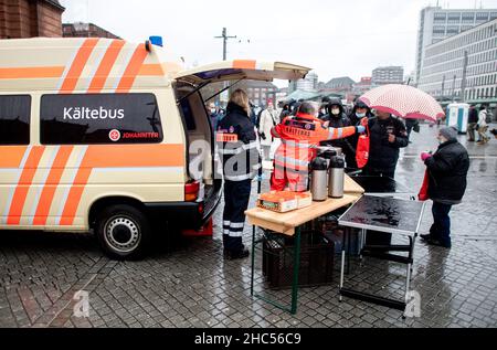 Brême, Allemagne.24th décembre 2021.Karin Stelljes, chef d'équipe au bus froid Johanniter, remet un sac rempli de nourriture à une personne dans le besoin la veille de Noël sur la piste de la gare principale.À plusieurs endroits de Brême, des repas chauds ou des sacs avec de la nourriture et des cadeaux sont distribués aux sans-abri et aux personnes dans le besoin à la veille de Noël.Credit: Hauke-Christian Dittrich/dpa/Alay Live News Banque D'Images