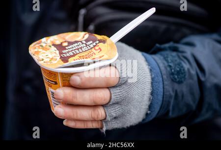 Brême, Allemagne.24th décembre 2021.Un homme sans abri tient un repas chaud qu'il a reçu du bus froid Johannître sur la piste à la gare principale la veille de Noël.À plusieurs endroits à Brême, des repas chauds ou des sacs avec de la nourriture et des cadeaux sont distribués aux sans-abri et aux personnes dans le besoin à la veille de Noël.Credit: Hauke-Christian Dittrich/dpa/Alay Live News Banque D'Images