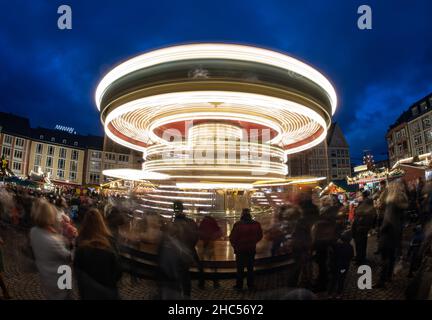 19 décembre 2021, Hessen, Francfort-sur-le-main : les visiteurs se tiennent au carrousel pour enfants au marché de Noël sur Römerberg (tourné avec une longue exposition).Alors que dans beaucoup d'autres endroits à Hesse, les marchés traditionnels ont été annulés en raison de la pandémie de Corona, le marché de Francfort a été autorisé à se dérouler sous certaines conditions.Photo : Boris Roessler/dpa Banque D'Images