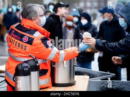 Brême, Allemagne.24th décembre 2021.Karin Stelljes, chef d'équipe au bus froid Johanniter, remet un repas chaud à une personne dans le besoin la veille de Noël sur la piste de la gare principale.À plusieurs endroits à Brême, des repas chauds ou des sacs avec de la nourriture et des cadeaux sont distribués aux sans-abri et aux personnes dans le besoin à la veille de Noël.Credit: Hauke-Christian Dittrich/dpa/Alay Live News Banque D'Images