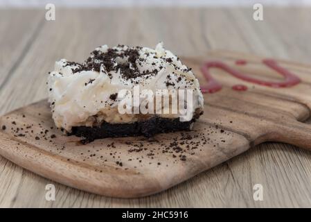 Terminer un repas avec un dessert sucré composé d'une tarte à la crème de banane servie sur un tableau de découpe et arrosée de chocolat. Banque D'Images