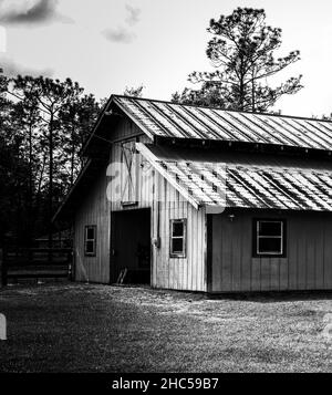 Photo en niveaux de gris d'une grange en bois sur un champ Banque D'Images