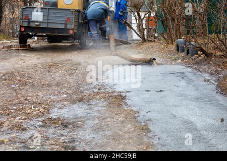 Une percée dans un tuyau avec de l'eau d'égout, une équipe de travailleurs communautaires utilisant une pompe et un tuyau pompe l'eau de la trappe d'égout.Copier l'espace. Banque D'Images