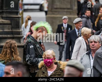 Un jeune homme regardant son téléphone avec un style punk mohican de cheveux parmi une foule de gens, Royal Mile, Edinburgh, Écosse, Royaume-Uni Banque D'Images