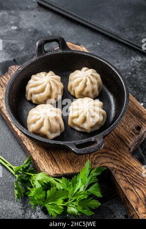 Dim sum farci de viande dans une casserole avec des herbes. Arrière-plan noir. Vue de dessus Banque D'Images