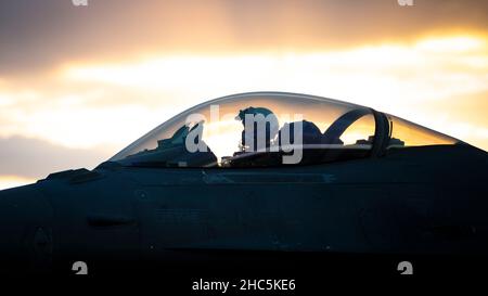 Un pilote de faucon de combat F-16C de la Force aérienne des États-Unis affecté à l'escadron de combat expéditionnaire 55th attend sur la ligne de vol pendant une opération de ravitaillement en fosse chaude dans le cadre d'un exercice d'emploi de combat Agile à un endroit non divulgué, le 21 décembre 2021.ACE est un concept opérationnel qui exploite des réseaux de bases aériennes bien établies et austères, des avions multi-capables, des équipements de pré-positionnement et des moyens de transport aérien pour déployer, disperser et manœuvrer rapidement des capacités de combat dans un théâtre.Associé aux activités de ravitaillement, d'armement et de maintenance limitée des avions, ACE élargit le nombre de bases de W Banque D'Images