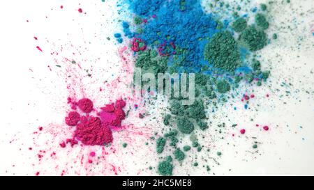 Vue de dessus des encres colorées sèches tombant dans une substance liquide blanche.Magnifique fond irisé de poudre verte, bleue et rose en fluide blanc Banque D'Images