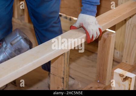 Constructeur à l'intérieur de bois homme en clouant des poutres en bois travaille pour la construction à l'aide d'un marteau à air de développement de logement Banque D'Images