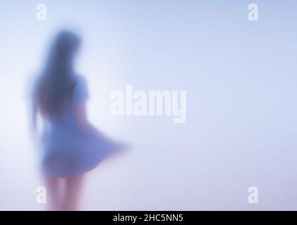 Femme dans une robe courte derrière le verre dépoli. Banque D'Images