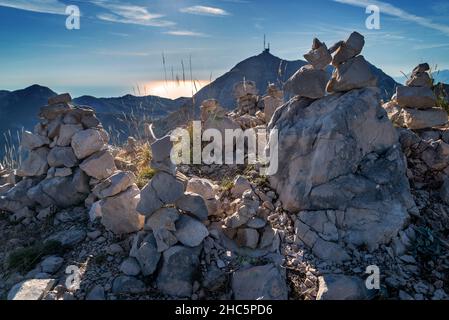 Petites piles de pierres, construit de façon créative au fil du temps par des visteurs au mausolée de Njego, parc national de Lovcen, regardant à l'ouest, rétroéclairé par le soleil couchant Banque D'Images