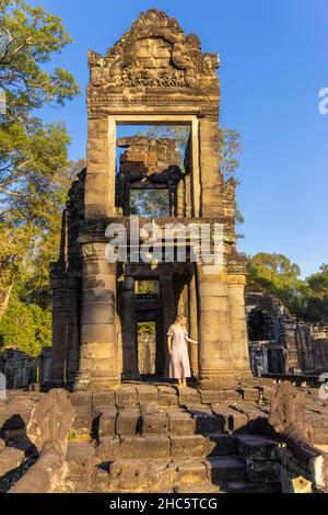 Touriste féminin dans les ruines du temple de Preah Khan dans le complexe d'Angkor, surcultivé par des arbres, Cambodge Banque D'Images