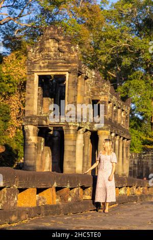 Touriste féminin dans les ruines du temple de Preah Khan dans le complexe d'Angkor, surcultivé par des arbres, Cambodge Banque D'Images