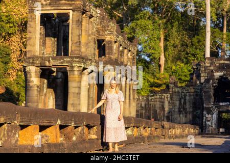 Touriste féminin dans les ruines du temple de Preah Khan dans le complexe d'Angkor, surcultivé par des arbres, Cambodge Banque D'Images