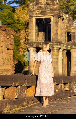 Touriste féminin dans les ruines du temple de Preah Khan dans le complexe d'Angkor, surcultivé par des arbres, Cambodge Banque D'Images