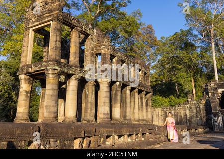 Femme khmère dans une robe traditionnelle dans les ruines du temple de Preah Khan dans le complexe d'Angkor, surcultivée par des arbres, Cambodge Banque D'Images