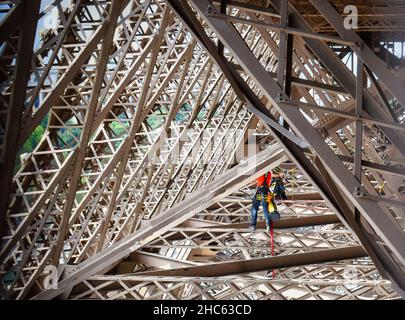 Trabajos de mantenimiento por dos operarios en la estructura metálica de la torre Eiffel en Paris, Francia Banque D'Images