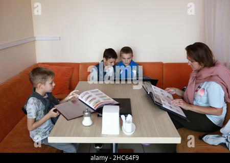 Mère avec trois fils qui choisissent la nourriture au menu dans le restaurant Banque D'Images