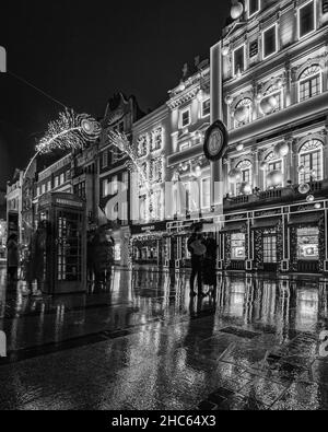 Un couple dehors sous la pluie sous un parapluie à l'extérieur du magasin Cartier à Londres. Banque D'Images