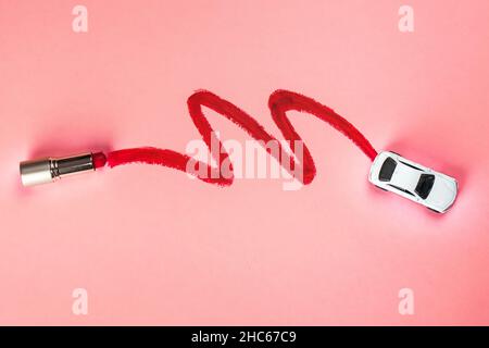 Vue aérienne d'une voiture blanche et de ses traces mises en évidence par un rouge à lèvres sur fond rose Banque D'Images