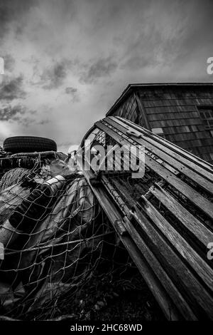 Cliché vertical d'une cage en bois endommagée dans un champ en niveaux de gris Banque D'Images