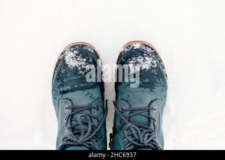 Gros plan de l'hiver mettez symétriquement des bottes bleues chaudes avec des lacets dans la neige, ce qui fait de l'empreinte sur le sol recouvert de neige.Arrière-plan étonnant Banque D'Images