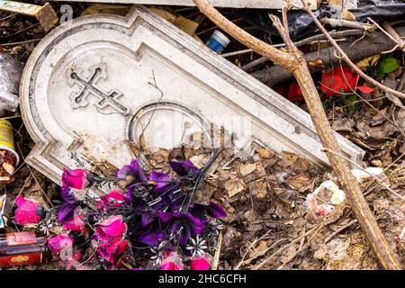 une vieille pierre tombale se trouve dans une pile de déchets à la périphérie d'un cimetière, foyer sélectif Banque D'Images