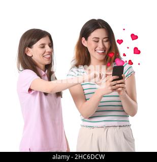 Belles jeunes femmes avec téléphone envoyant un message d'amour sur fond blanc Banque D'Images