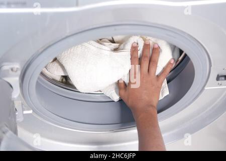 mettre une serviette et des chiffons dans un lave-linge. Banque D'Images