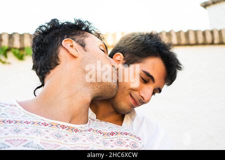 Petit ami embrassant son partenaire dans la joue.Jeune couple gay amoureux.Portrait romantique en été Banque D'Images