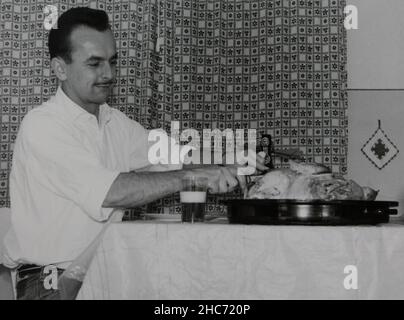 Veille de Noël en Allemagne 1962.La dinde de Noël traditionnelle est coupée avec un couteau par mon père dans la cuisine. Banque D'Images