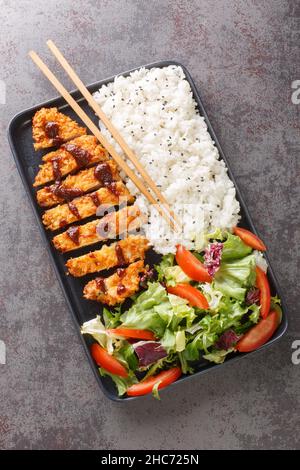 Le katsu de poulet est un plat traditionnel japonais servi avec de la salade de riz et de légumes dans l'assiette sur la table.Vue verticale du dessus Banque D'Images