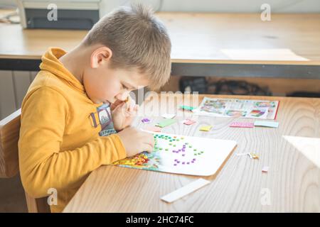 Petit garçon en étant créatif faire maison faites-le vous-même mosaïque de dinosaure.Soutenir la créativité, l'apprentissage par la pratique, l'apprentissage par l'expérience.Aide Banque D'Images