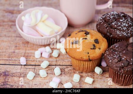 muffins au chocolat et muffin à la vanille à côté des guimauves sur fond de bois Banque D'Images