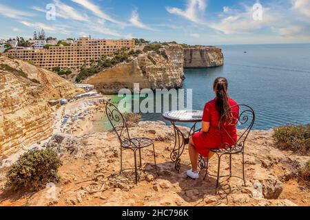 Vue arrière d'une dame à la plage en forme de fer à cheval Praia do Carvoeiro à Lagoa, Algarve, Portugal Banque D'Images