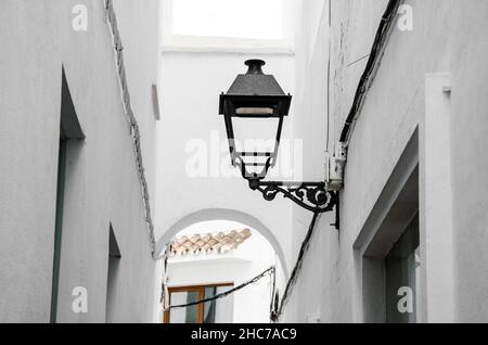 Lampe de rue noire attachée à un bâtiment blanc dans une rue étroite, Marbella, Espagne Banque D'Images