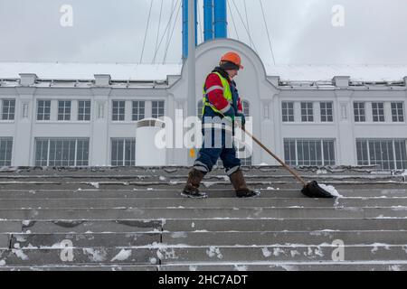 Moscou, Russie.25th décembre 2021 un employé des services communautaires enlève de la neige en arrière-plan le bâtiment du centre d'art contemporain GES-2 à Moscou, en Russie Banque D'Images