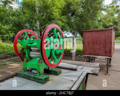 Photo de stock de la vue latérale de la couleur verte et rouge manuel de la canne à sucre fabricant ou de la machine d'extraction sur le côté de la route du village indien rue pendant bri Banque D'Images