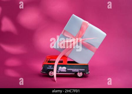 Kiev Ukraine - 11 mars 2021. Modèle de jouet de Volkswagen Type 2, T1, pick 2 avec grande boîte cadeau sur le tableau sur fond rose vif avec ombres. Banque D'Images