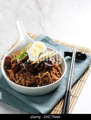 Jajangmyeon ou Jajangmyeon, nouilles coréennes avec sauce soja noire.Garniture à l'œuf de caille, au concombre, à la graine de sésame et à l'oignon de printemps. Banque D'Images