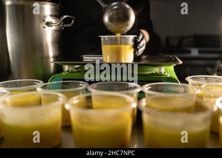 Livraison de nourriture au restaurant.Le chef prépare et prépare les aliments dans des plats jetables sur une balance pesant la portion requise.Gros plan d'un Banque D'Images