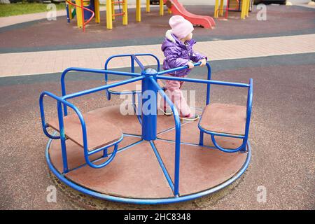 enfant ennuyé dans un carrousel sur une aire de jeux par une journée ensoleillée d'automne Banque D'Images