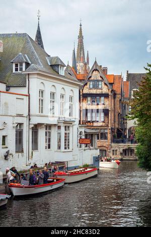 Vue panoramique sur un canal avec des bateaux touristiques dans le centre de la ville historique de Bruges en Flandre, Belgique. Banque D'Images