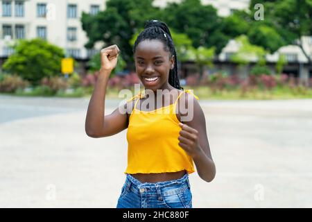 Danse africaine américaine jeune femme adulte avec des tresses en plein air en été dans la ville Banque D'Images