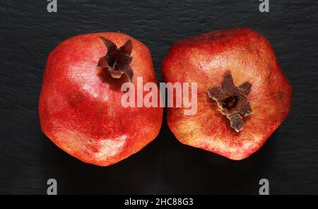 Photographie de deux grenades entières sur fond d'ardoise pour des illustrations alimentaires Banque D'Images