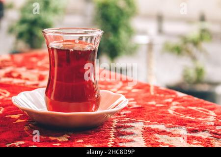 Thé turc traditionnel en verre spécial en forme de tulipe sur nappe rouge.Mise au point sélective.Arrière-plan flou avec espace de copie Banque D'Images