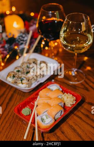 Décor de cuisine japonaise traditionnelle sur fond sombre.Petits pains à sushi au vin rouge dans un verre haut.Cadre alimentaire asiatique.Soirée dîner. Perte de sushi Banque D'Images
