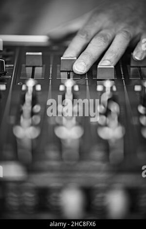 Mise au point sélective verticale en niveaux de gris des faders sur un panneau de mixage réglé à la main Banque D'Images